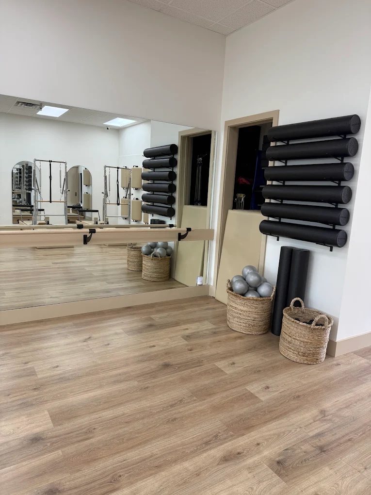 Barre and mirrored wall with woven baskets and foam rollers at the studio